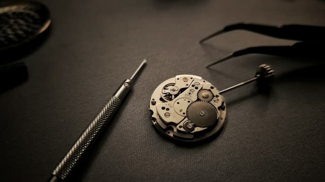 A close-up photograph of hands working carefully on a mechanical object.